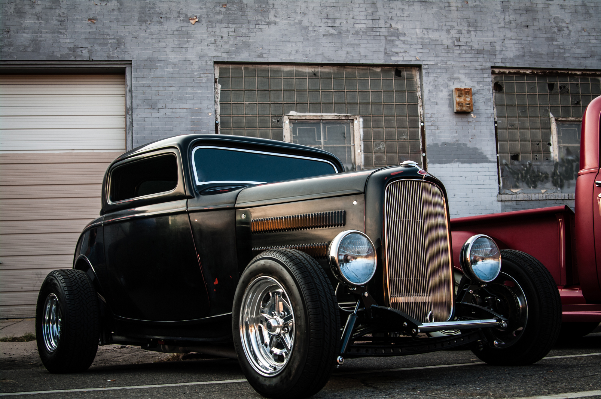 Vintage black hot rod car parked outside.