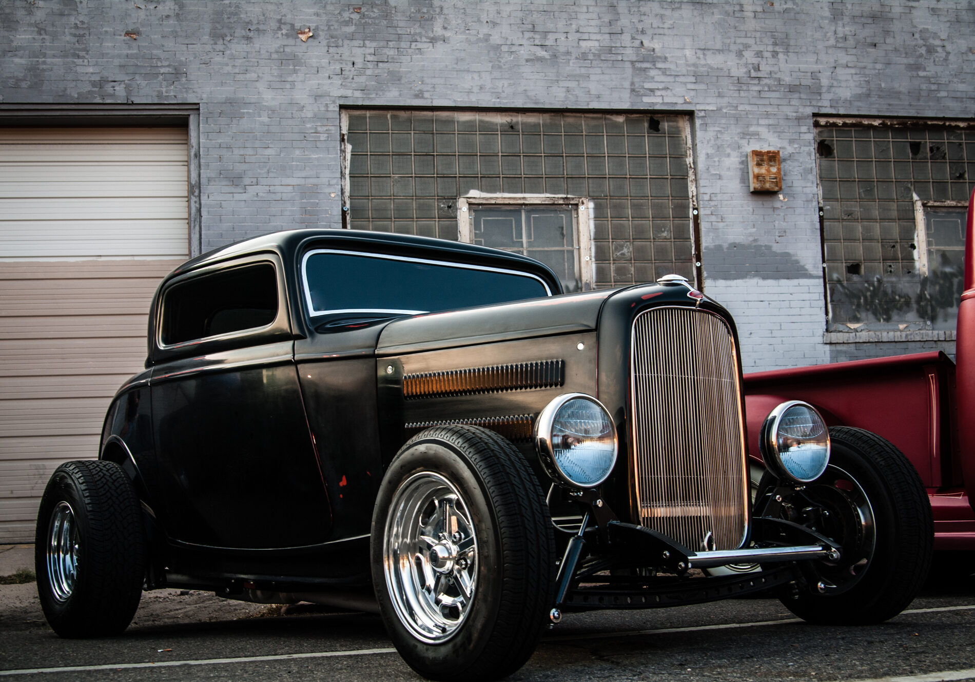 Classic black vintage hot rod car parked near an industrial building. Classic black vintage hot rod car parked near an industrial building.